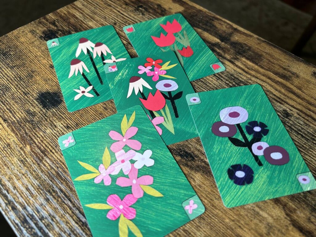 The cards, much like the board, are covered in paper cutout art.