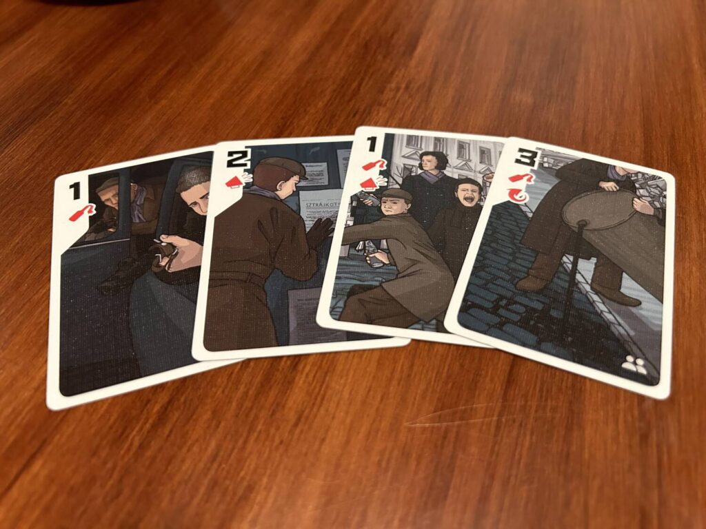 Four player cards, each with a numerical value and one or two icons in the upper left corner.