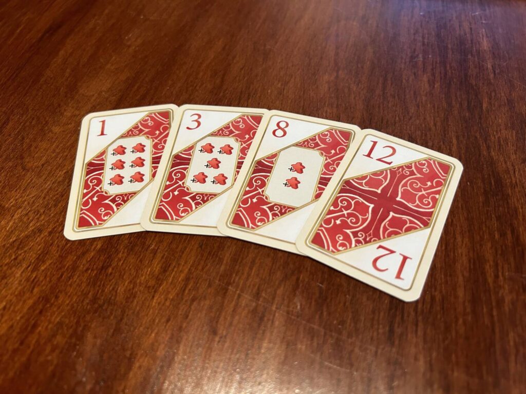The bidding cards show numbers in the upper corners and anywhere between zero and six meeples in the middle.