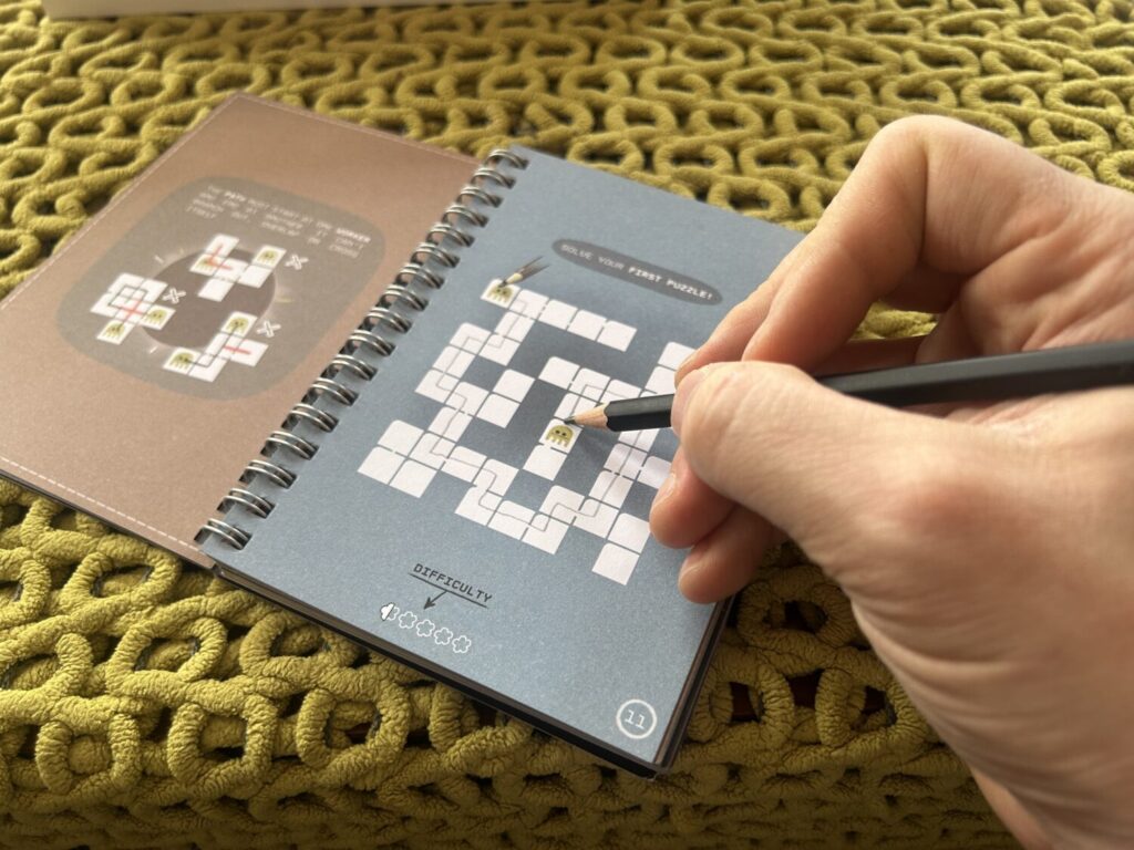 A hand holding a puzzle completes drawing a line from one alien to another through the simplest puzzle in the book.