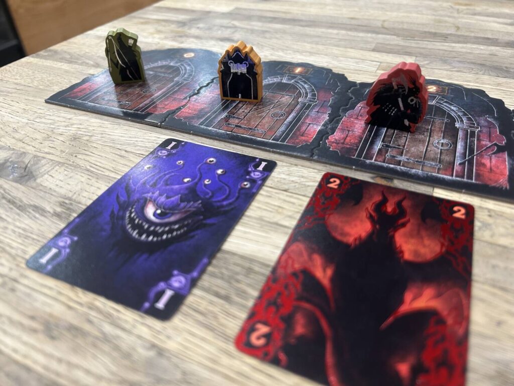 A series of irregularly shaped door tiles sit side-by-side on a table, with wooden meeples screenprinted with the shadows of different RPG classes. Several cards sit below some of the doors.