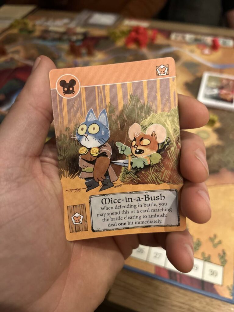 A detail photo of the artwork from a card called "Mice-in-a-Bush," which features an excellent illustration of a mouse holding a knife to the back of a surprised cat.