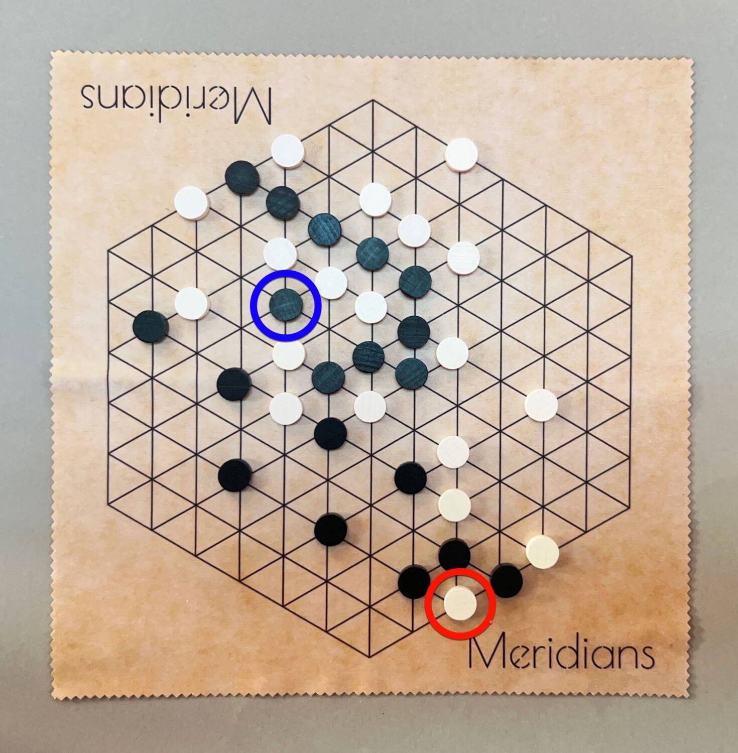 Late midgame; the black piece circled in blue and the white piece circled in red are both threatened.