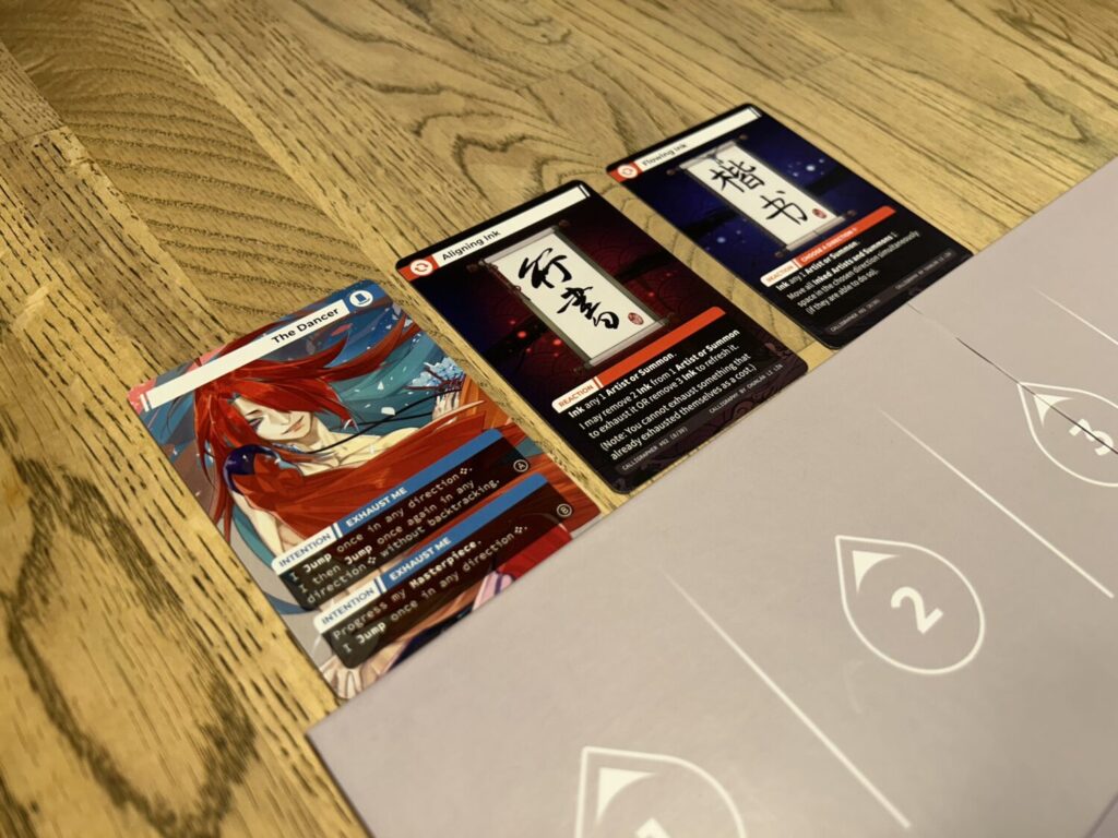 Three cards sit above a cardboard rectangle.