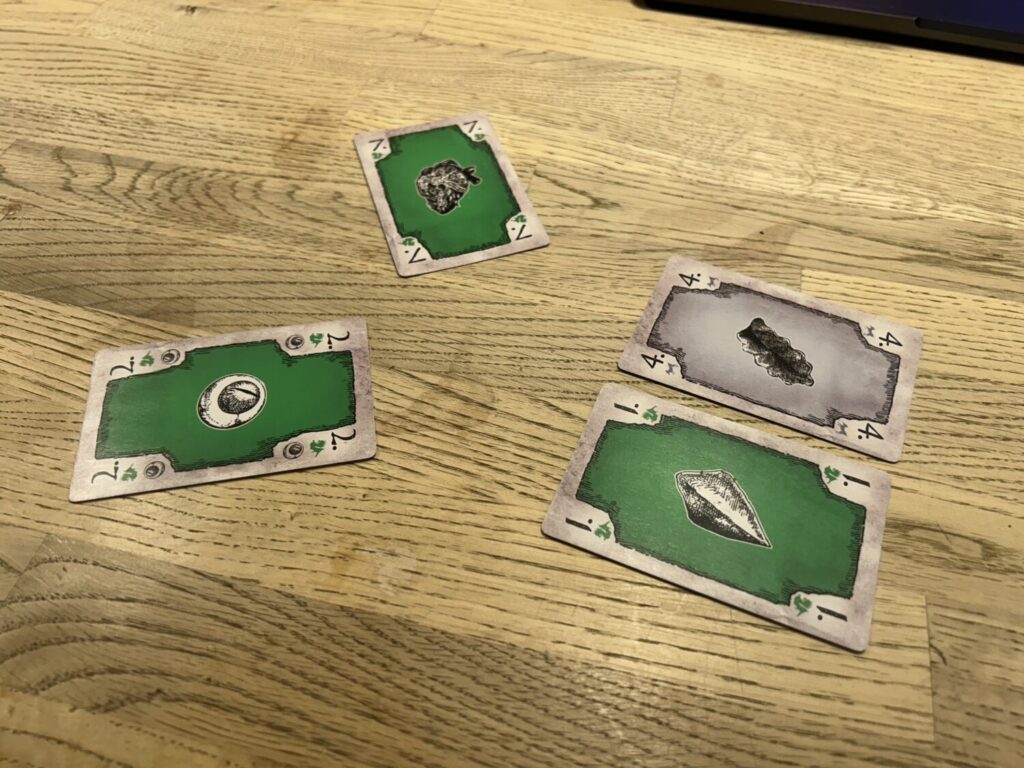 The same four cards sit on the table, but now the facedown card has been revealed. It is grey.