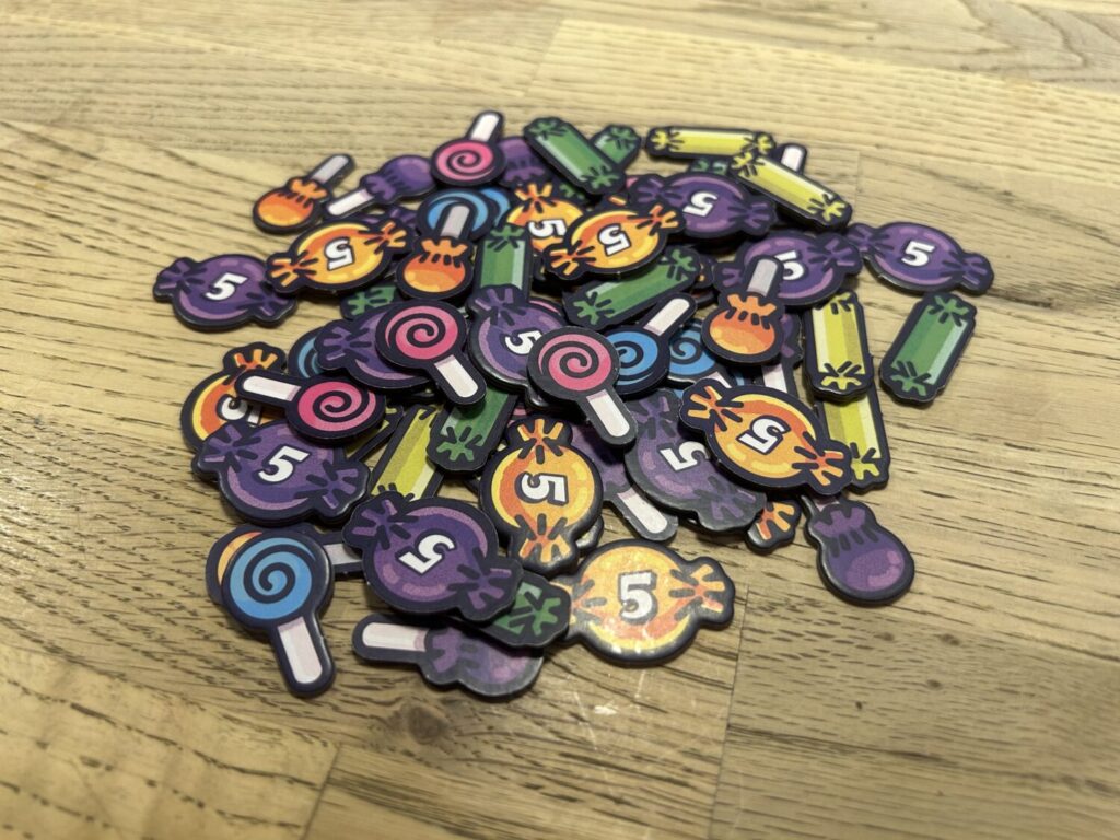 A pile of candy-shaped scoring tokens sits on a wooden table.