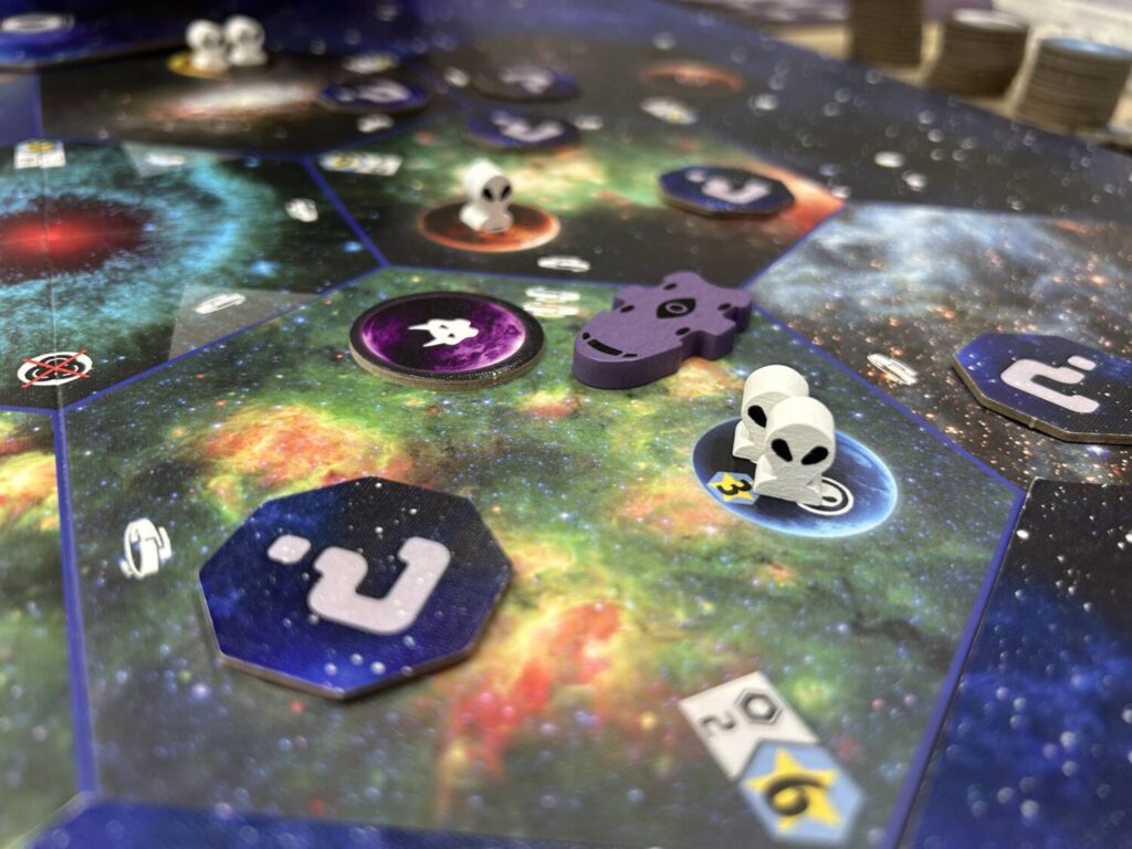 A closer shot of one region, with alien figures on several planets and a purple ship, made out of wood, floating in space between the planets.