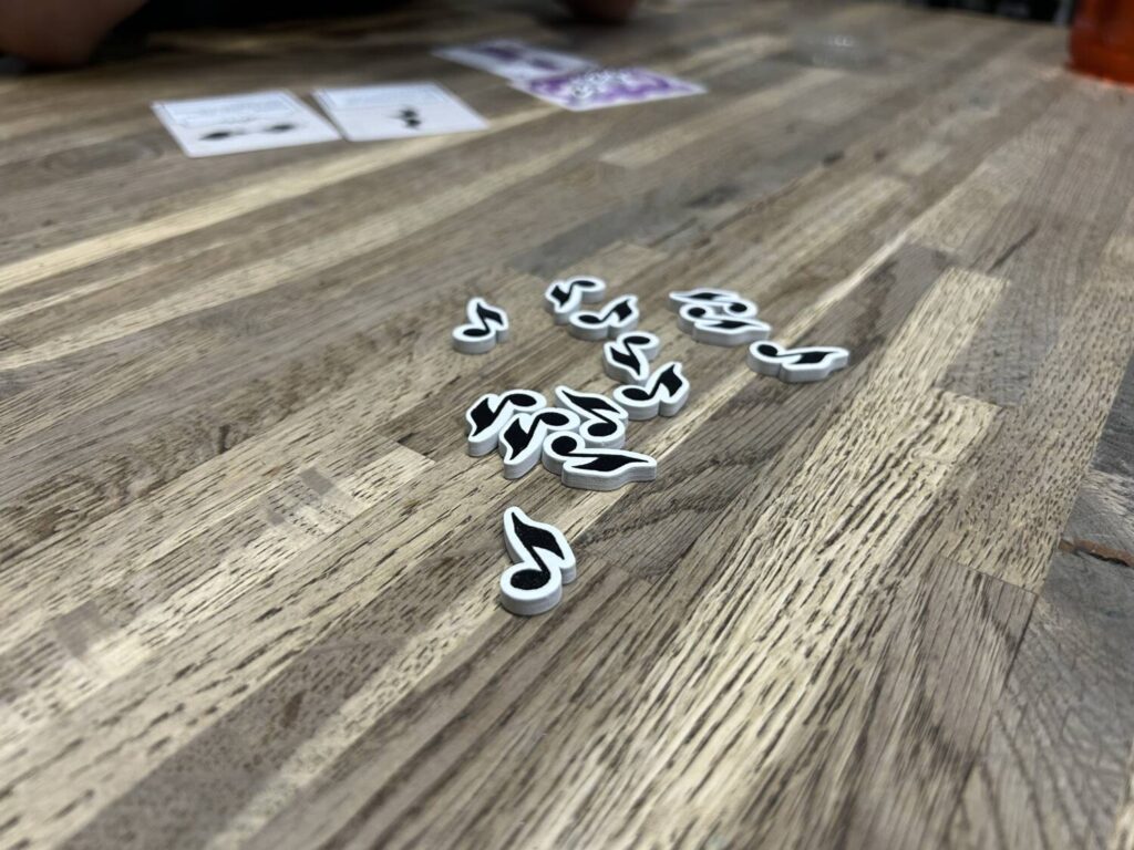 A pile of wooden tokens in the shape of eighth notes sit on a wooden table.