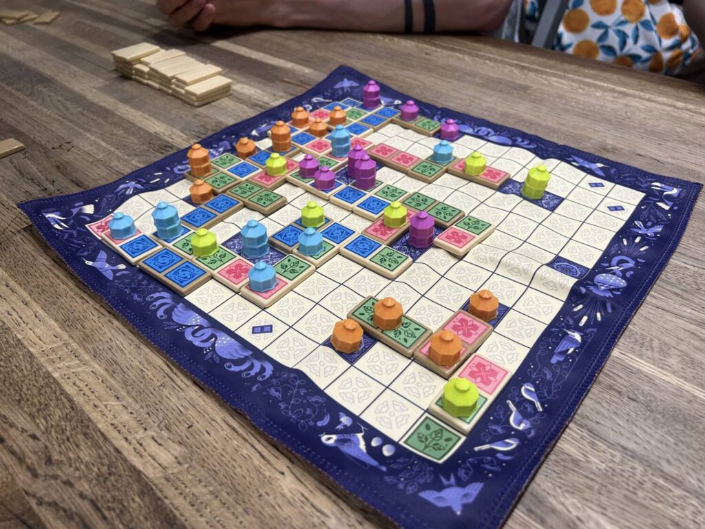 A cloth board partially covered by dominoes and plastic gazebos.