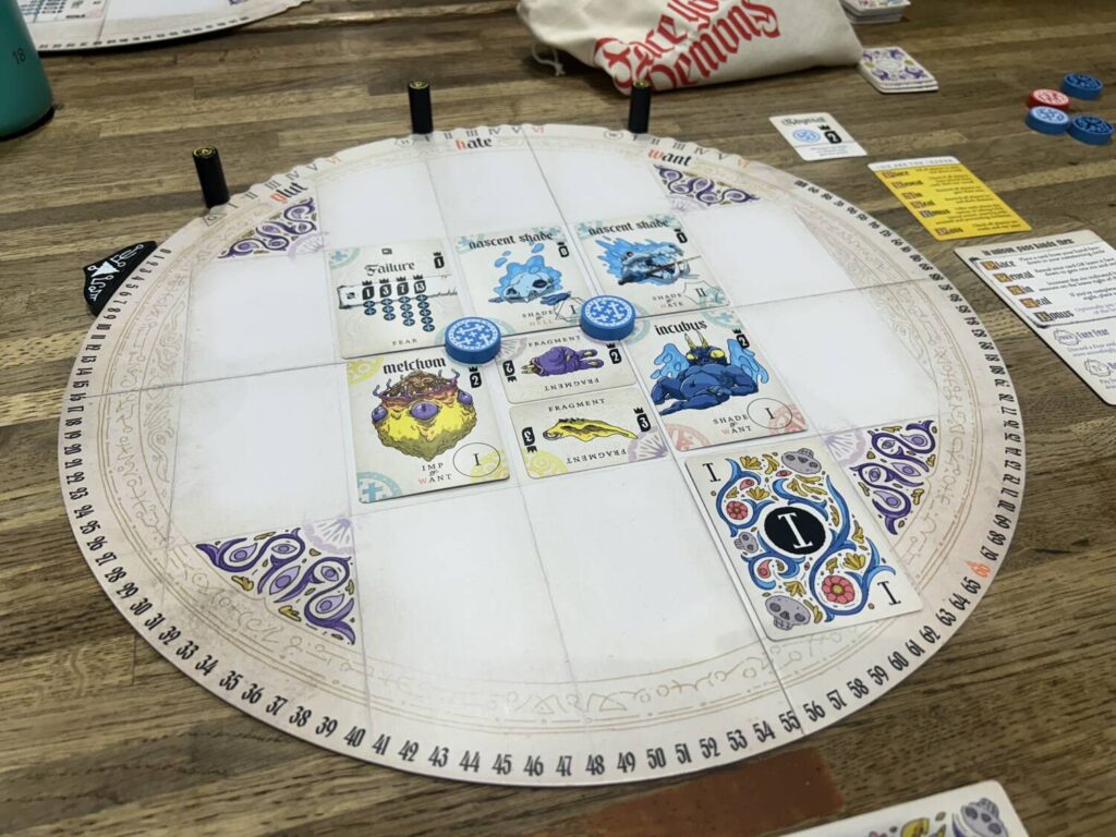A circular player board, with several boldly-illustrated cards sitting in their slots, on a wooden table.