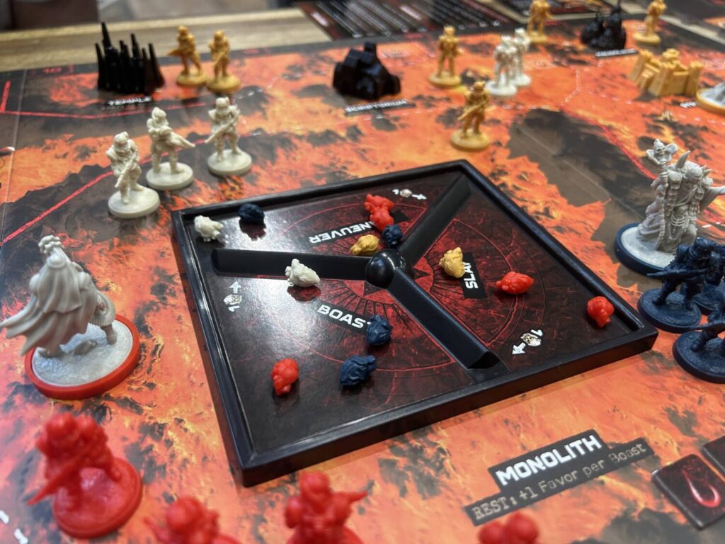 The board under the Monolith, with small plastic hearts in each of its three sections. Each section is labelled with an action.
