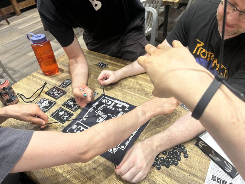A group of hands and arms float in space above the cloth Playthings board.
