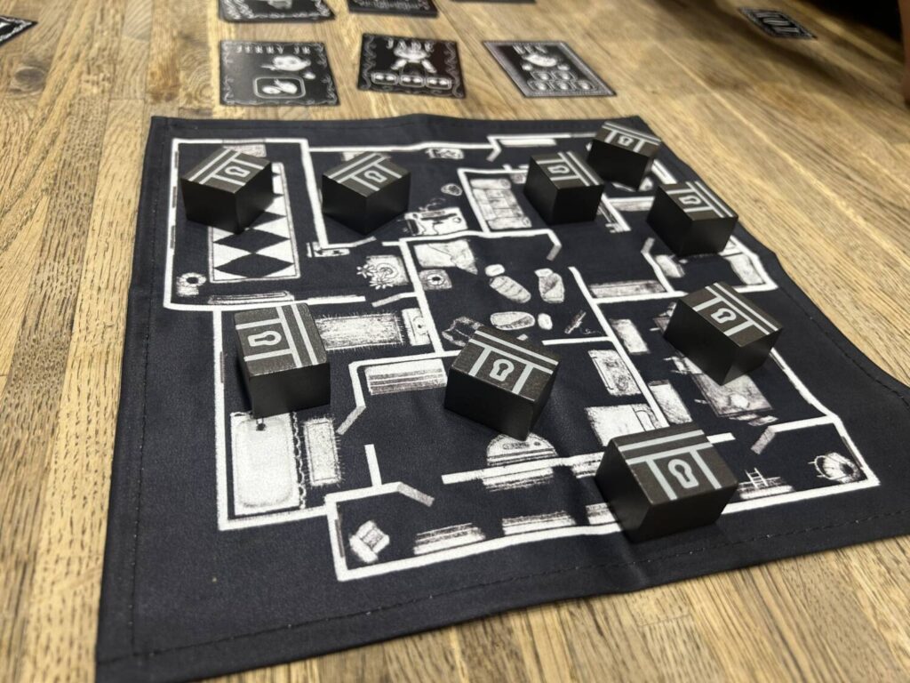 The Playthings mat, white lines on black fabric, shows the floorplan for a house. Wooden chests with treasures on the underside sit in the various rooms.